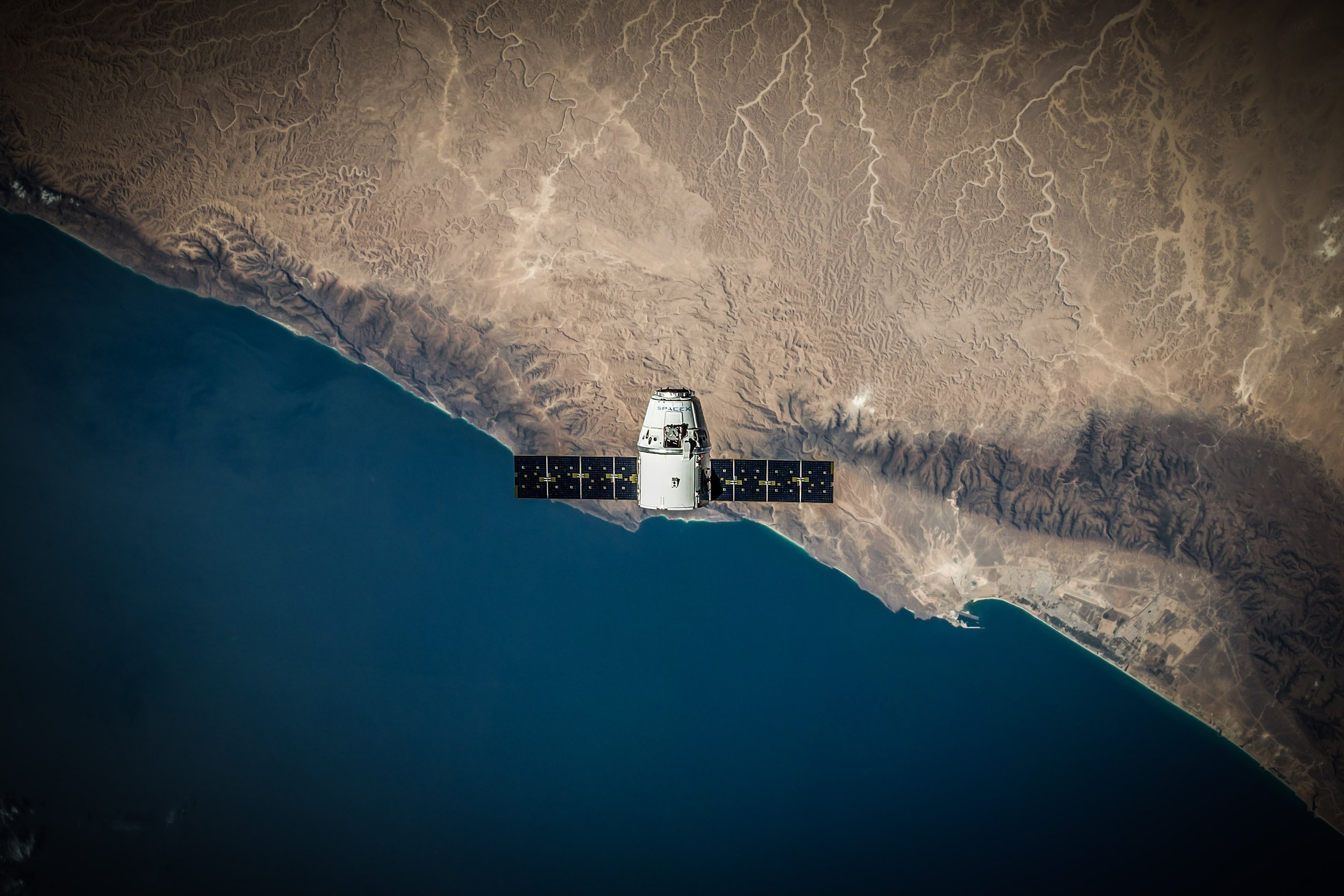 A SpaceX Dragon spacecraft above the coastline of Earth
